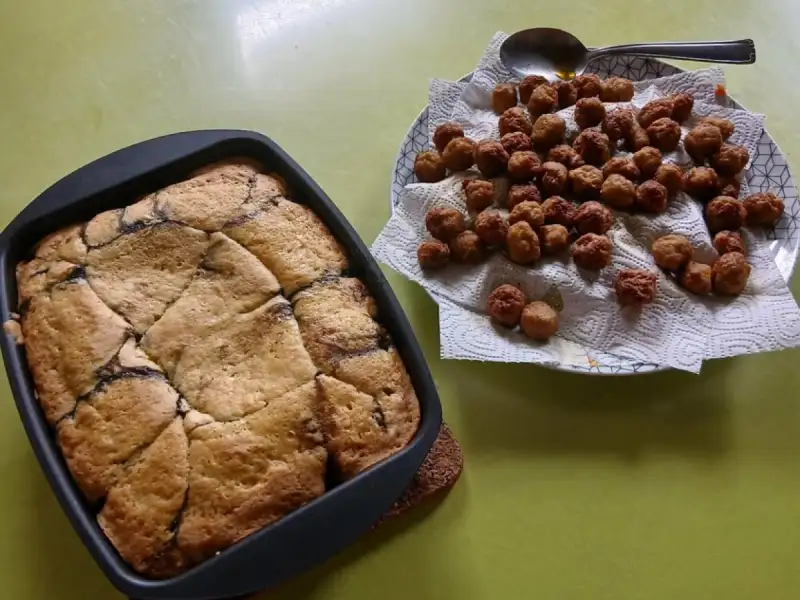 Golden cherry cake in a square pan, next to a plate of little meatballs