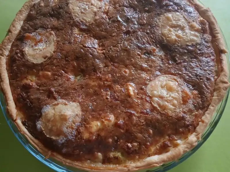 Golden clean-out-the-fridge quiche topped with goat cheese rounds, in a glass dish