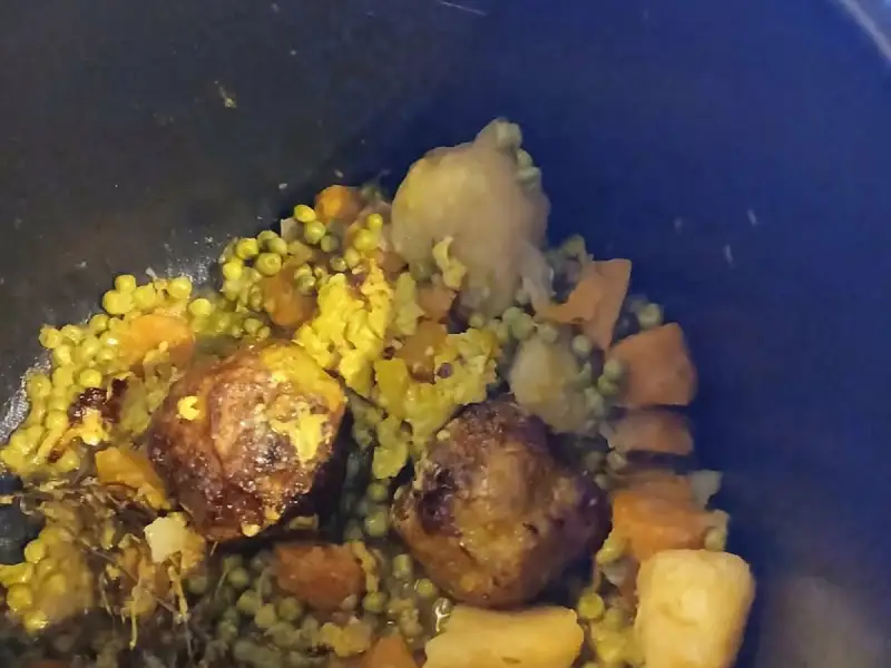 Meatballs with peas, carrots and potatoes with turmeric, simmered in a black Dutch oven