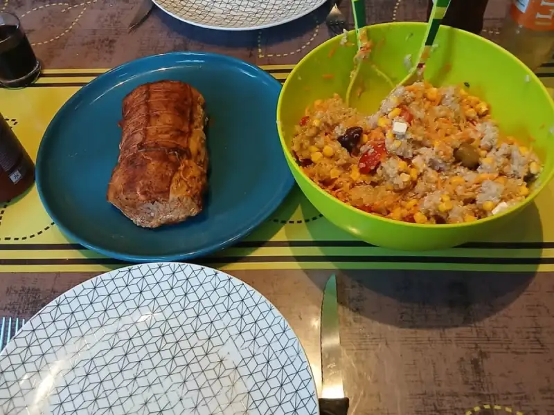 Golden oven-baked salmon roast on a blue plate next to a bowl of rice salad with corn, tomatoes, feta and olives