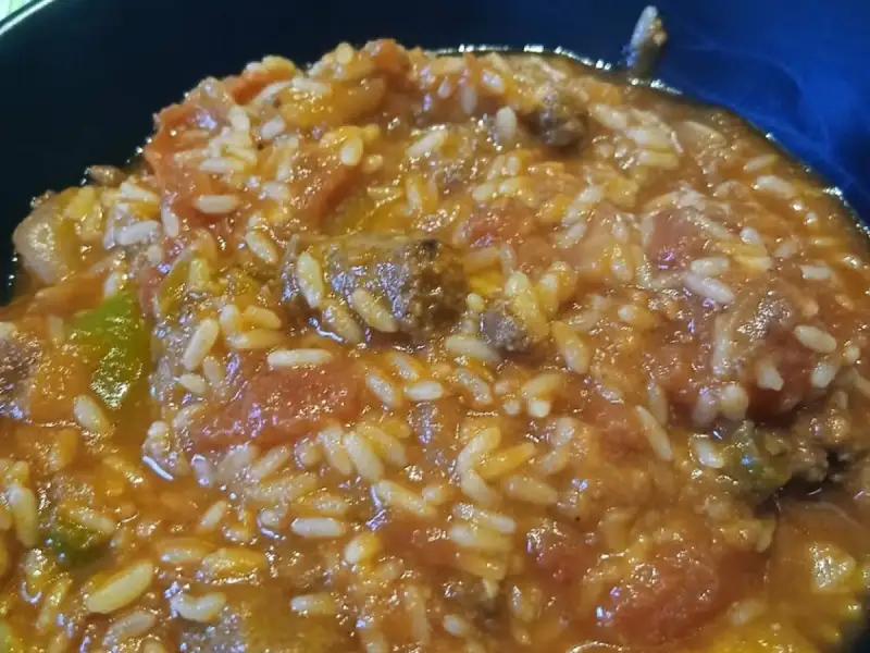 Shallow bowl of tomato rice braised with chunks of beef and bell peppers