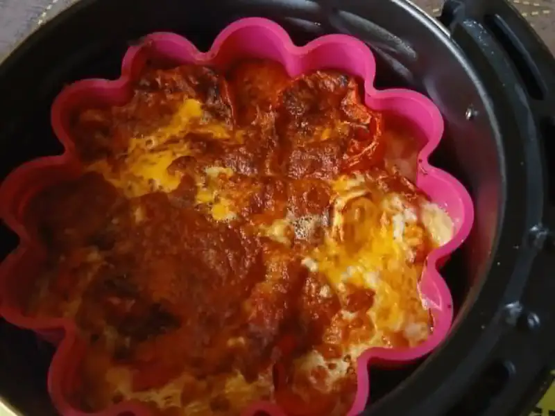 Golden cheesy tomato clafoutis in a pink silicone mold, in an air fryer basket